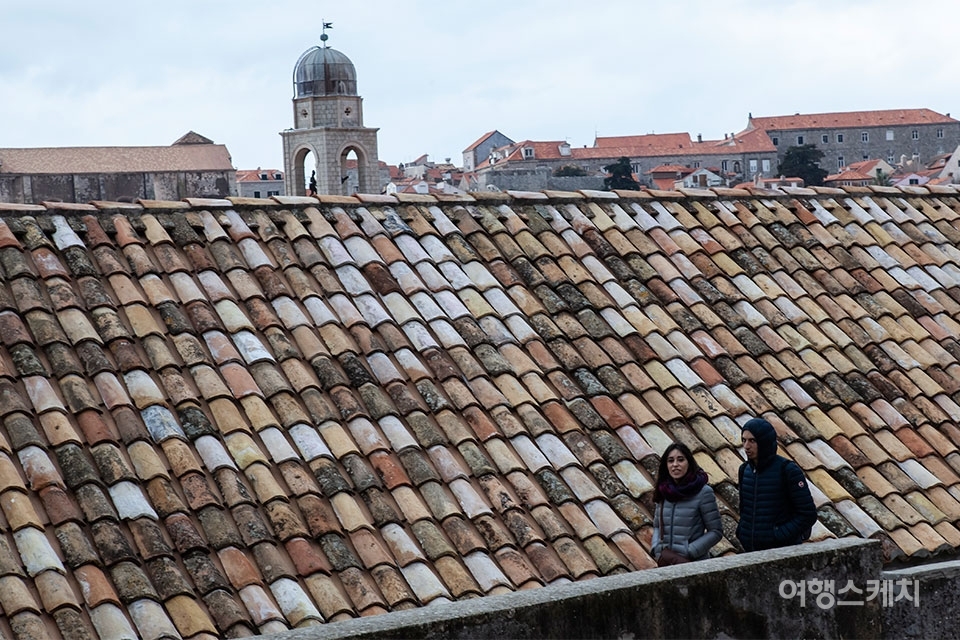 시간의 더께가 쌓인 기와지붕과 성벽투어 중인 여행자들. 사진 / 김수남 여행작가
